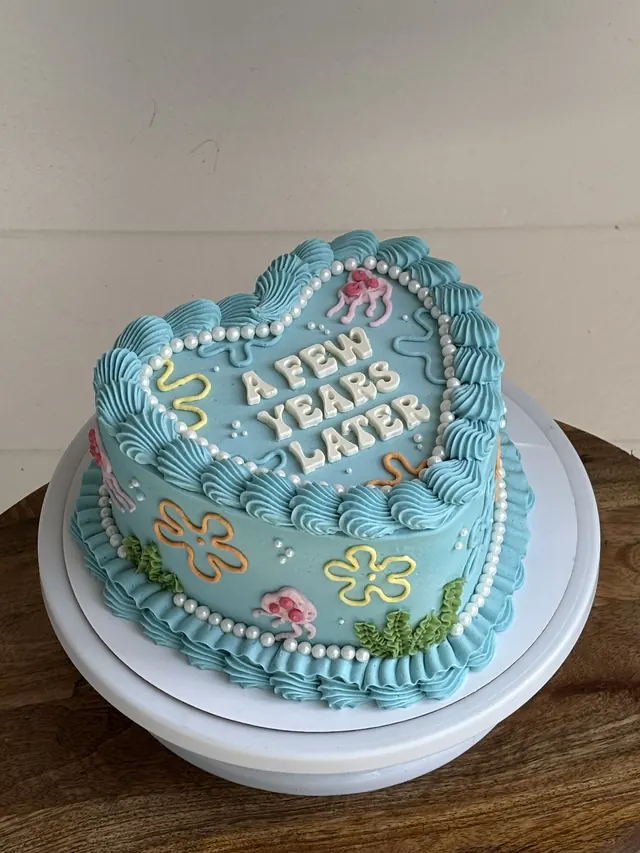 Blue heart cake with piped flowers, pearls and "A FEW YEARS LATER."