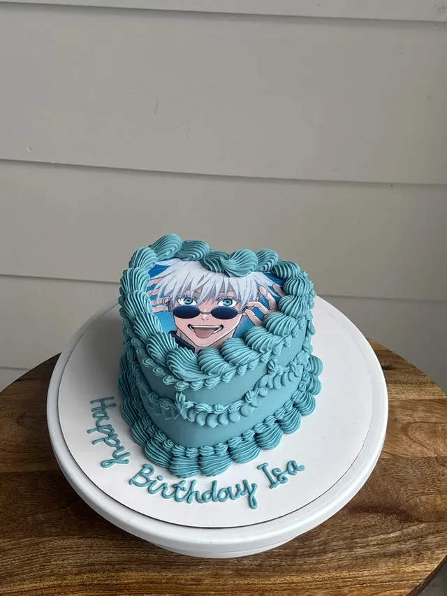 Teal heart cake with an edible anime photo and a birthday message on the board