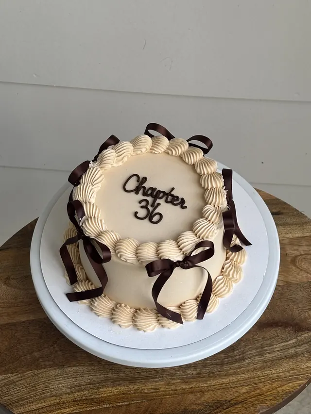 Peach round cake with brown bows and "Chapter 36."