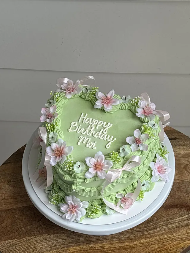 Green heart cake with pink blossoms, pink bows and a birthday message