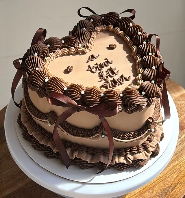 Mocha heart cake with chocolate piping, brown bows, pearls and coffee beans