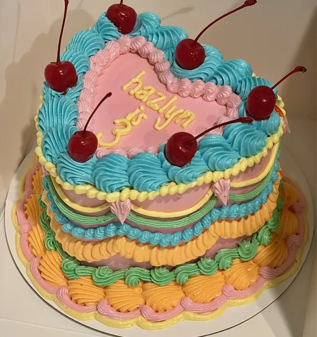 Heart cake piped in teal, pink, yellow, green and orange, with cherries and a 3rd birthday message