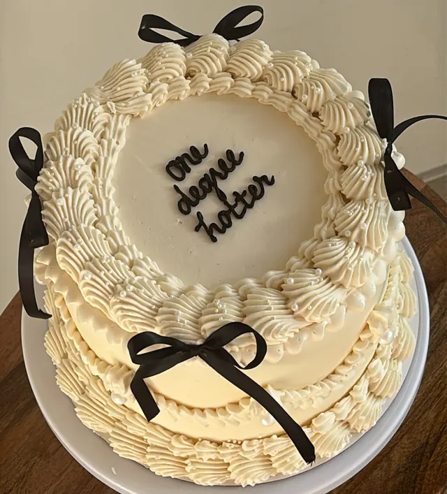 Ivory round cake with black bows and "one degree hotter."