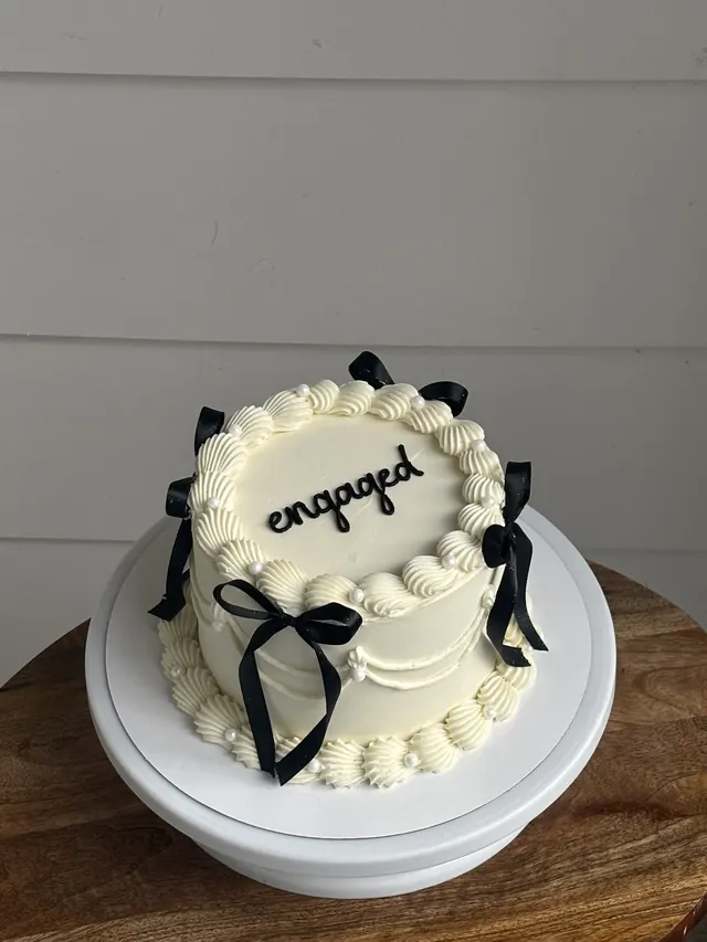 Ivory round cake with black bows and "engaged."