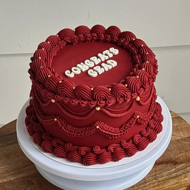 Deep red cake with gold pearls and "Congrats Grad" in white letters