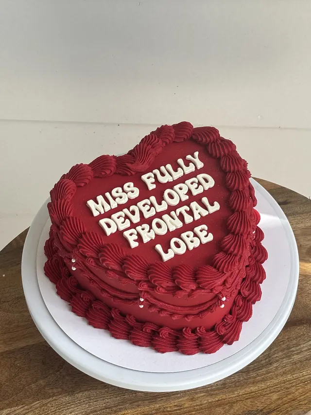 Red heart cake with "MISS FULLY DEVELOPED FRONTAL LOBE" in white letters