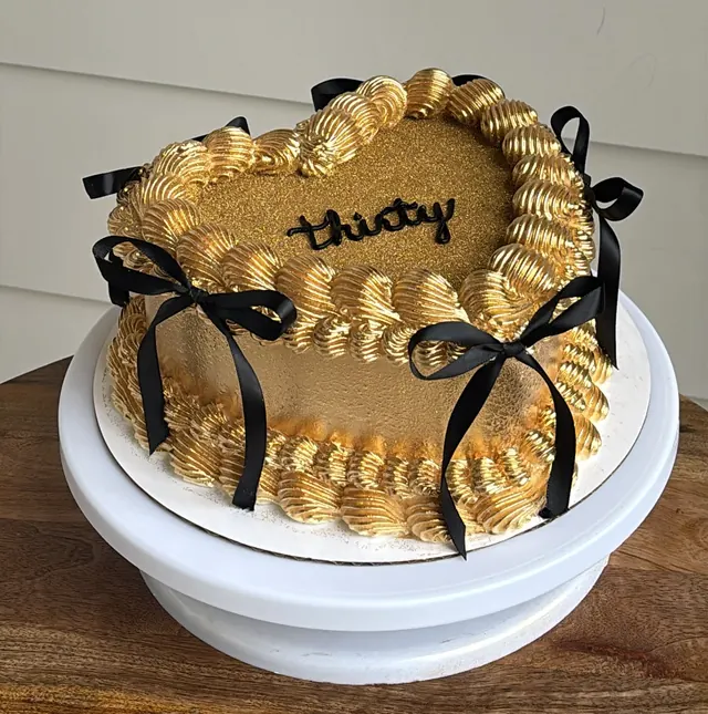Gold heart cake with black bows and "thirty."