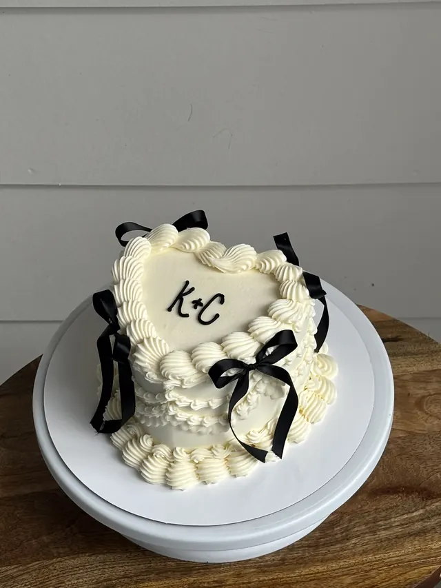 Ivory heart cake with black bows and the couple's initials