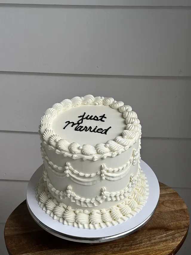Tall ivory round cake with swag piping and "just married."