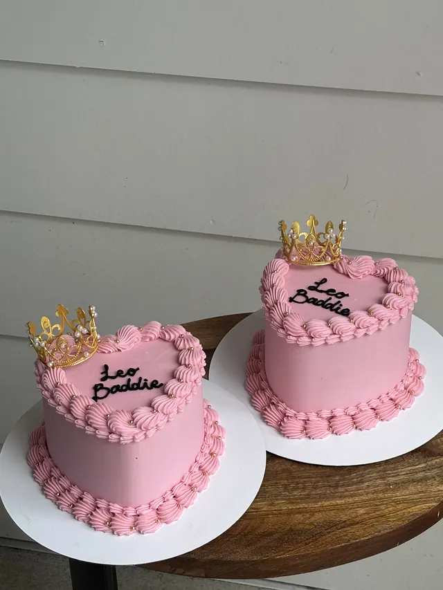 Two small pink heart cakes with gold crowns and "Leo Baddie."