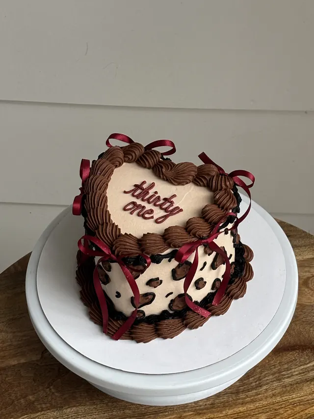 Cream heart cake with chocolate piping, leopard print sides, burgundy bows and "thirty one."