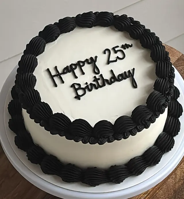 White round cake with black shell borders and "Happy 25th Birthday."