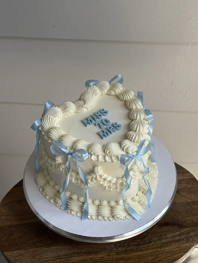 Ivory heart cake with blue bows and "MISS TO MRS."