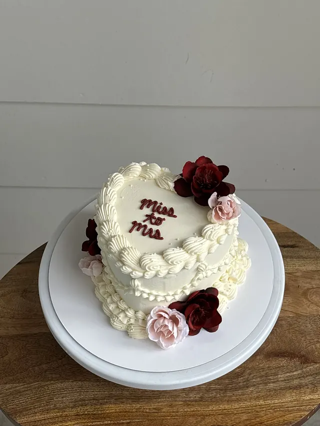 Ivory round cake with red and pink roses and "miss to mrs."