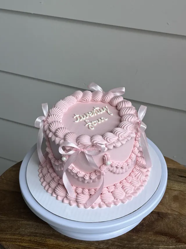 Pink cake with pink bows, ruffles and "twenty four."