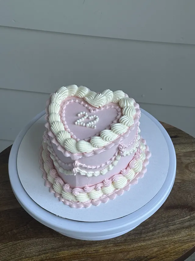 Pink and white heart cake with the age written in pearls