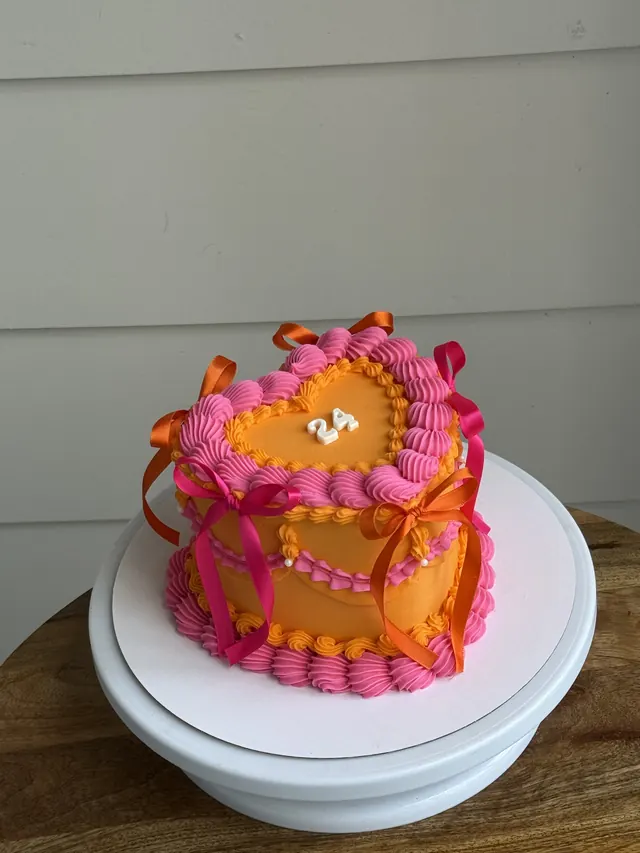 Pink and orange heart cake with orange and pink bows and a 24