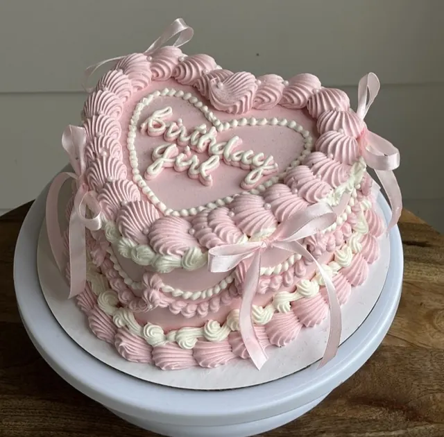 Pink heart cake with a pearl heart outline around "Birthday Girl" and pink satin bows
