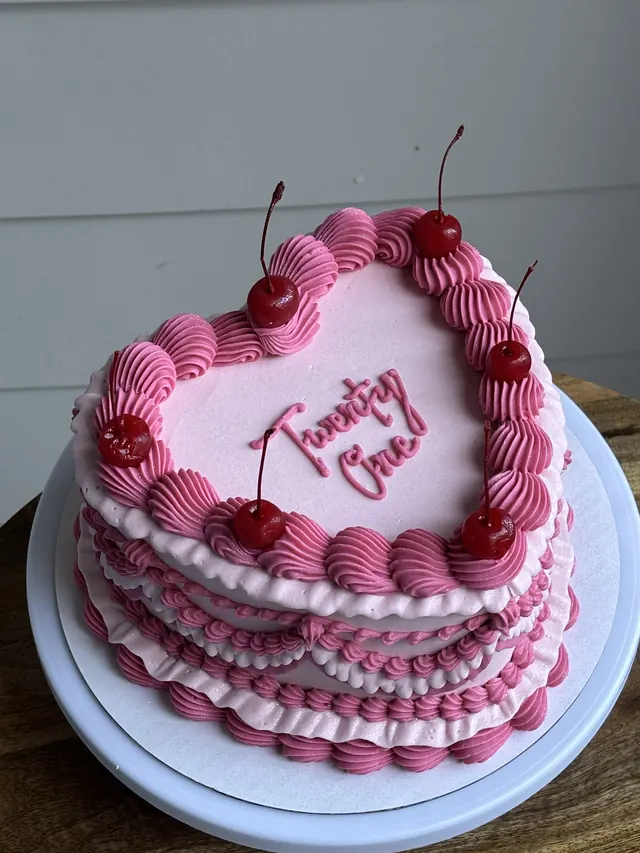 Pink heart cake with deep pink shell borders, cherries and "Twenty One."