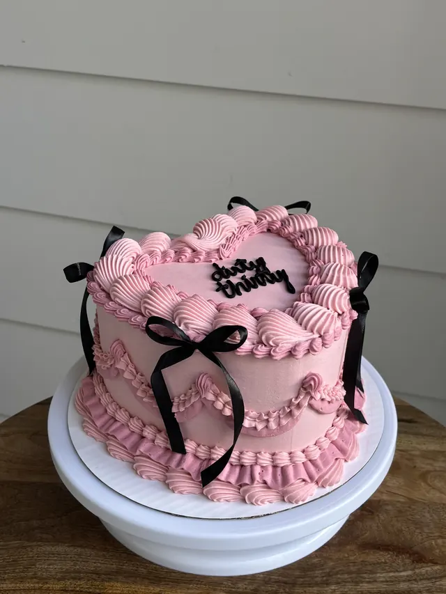 Pink heart cake with black bows and "dirty thirty."