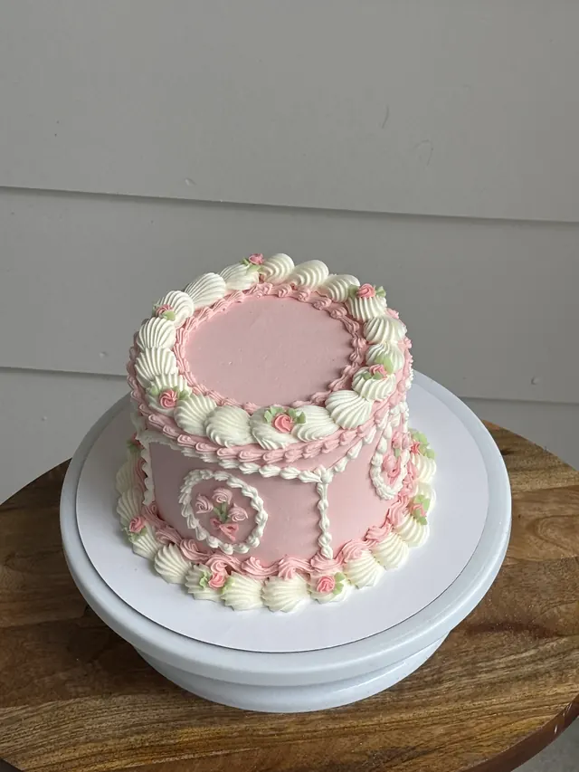 Pink round cake with ivory piping and small pink roses