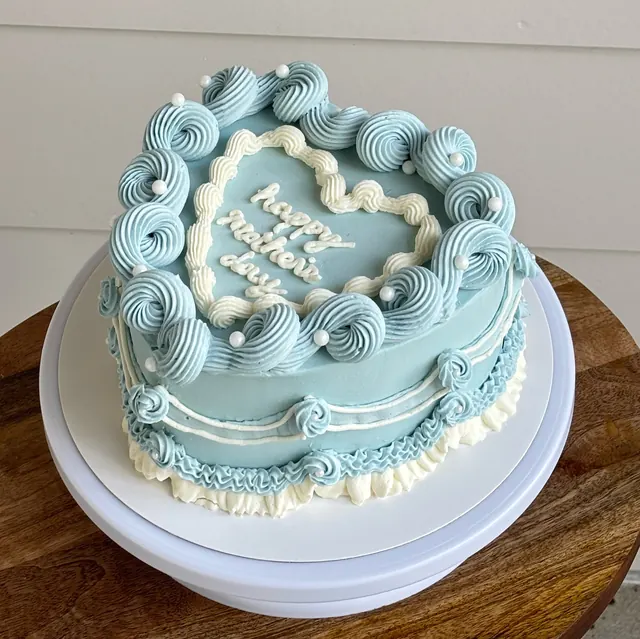 Powder blue heart cake with white piping and "happy mother's day."
