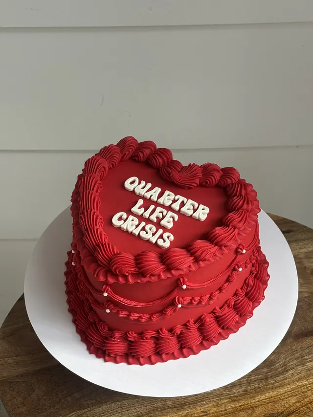 Red heart cake with "QUARTER LIFE CRISIS" in white block letters