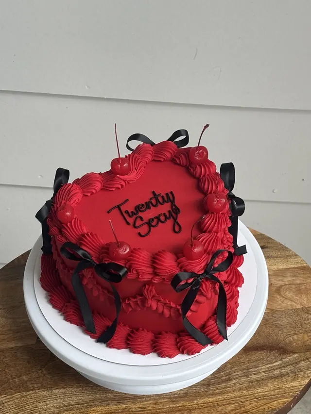 Red heart cake with cherries, black bows and a birthday message