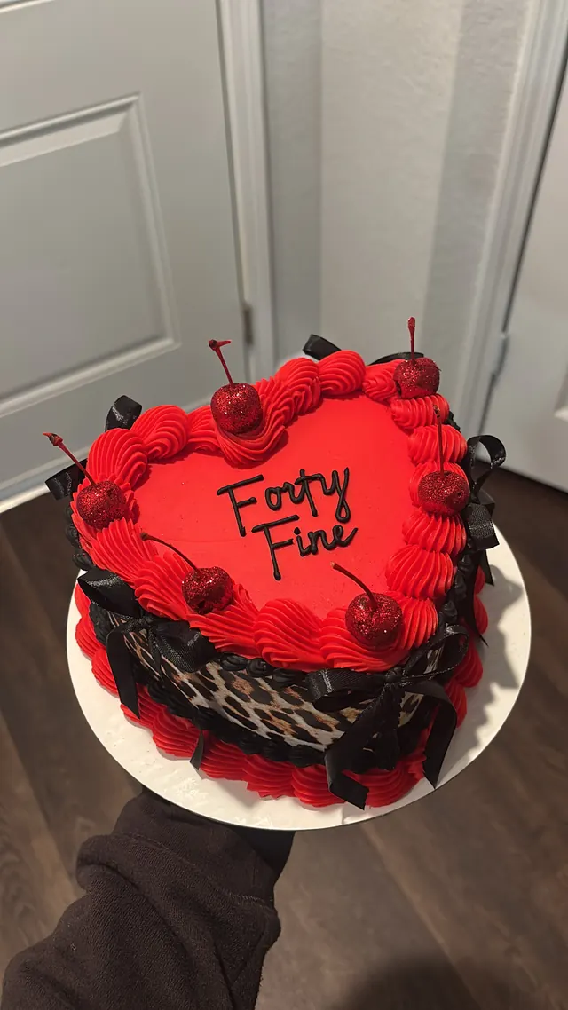 Red heart cake with leopard print sides, black bows, glitter cherries and "Forty Fine."
