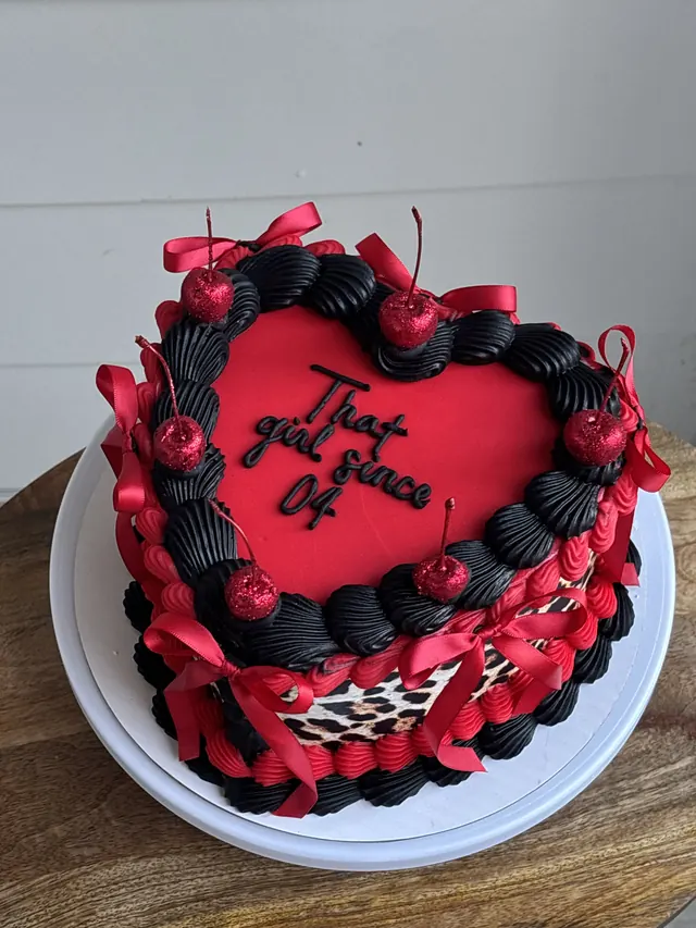 Red and black heart cake with leopard print, cherries, red bows and "That girl since 04."