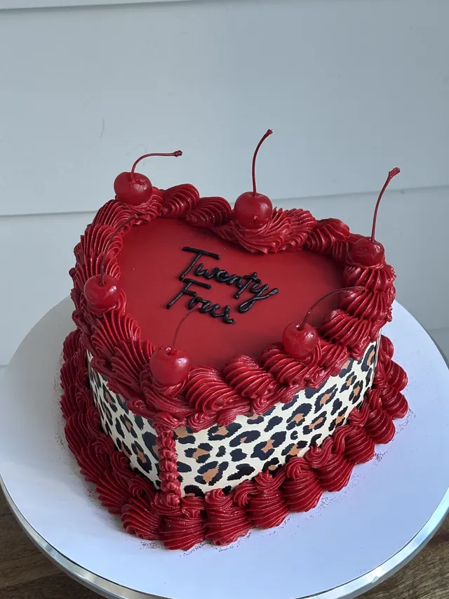 Red heart cake with leopard print sides, cherries and "Twenty Four."