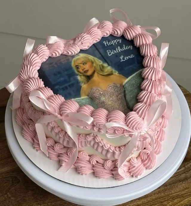 Pink heart cake with an edible photo of Sabrina Carpenter, a birthday message and pink bows