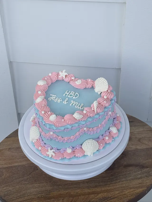 Pink and blue heart cake with seashells and a birthday message for two