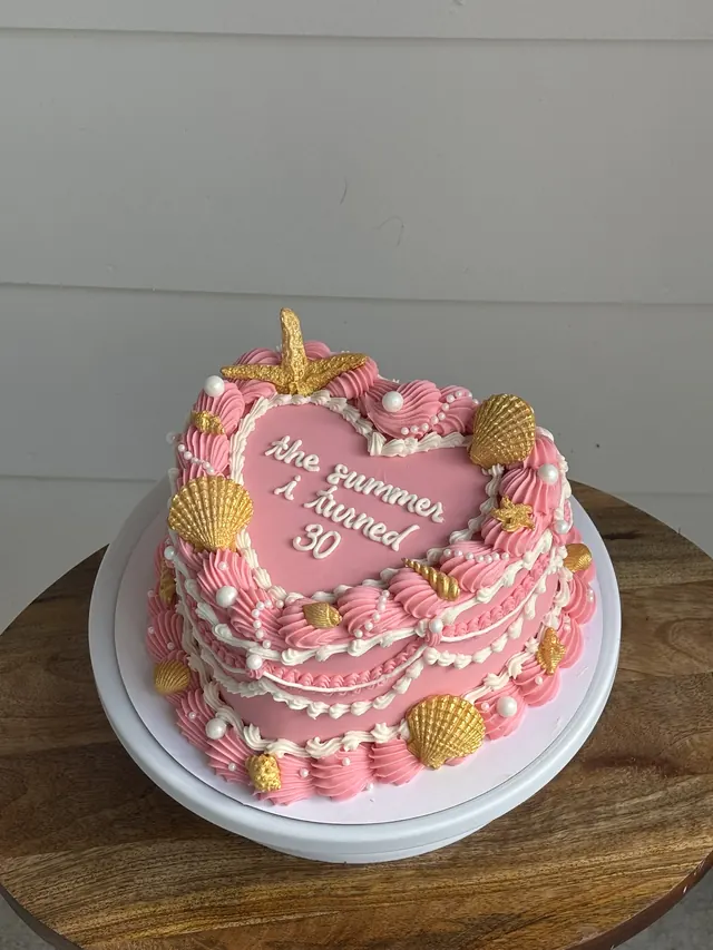 Pink heart cake with gold seashells, a starfish and "the summer I turned 30."