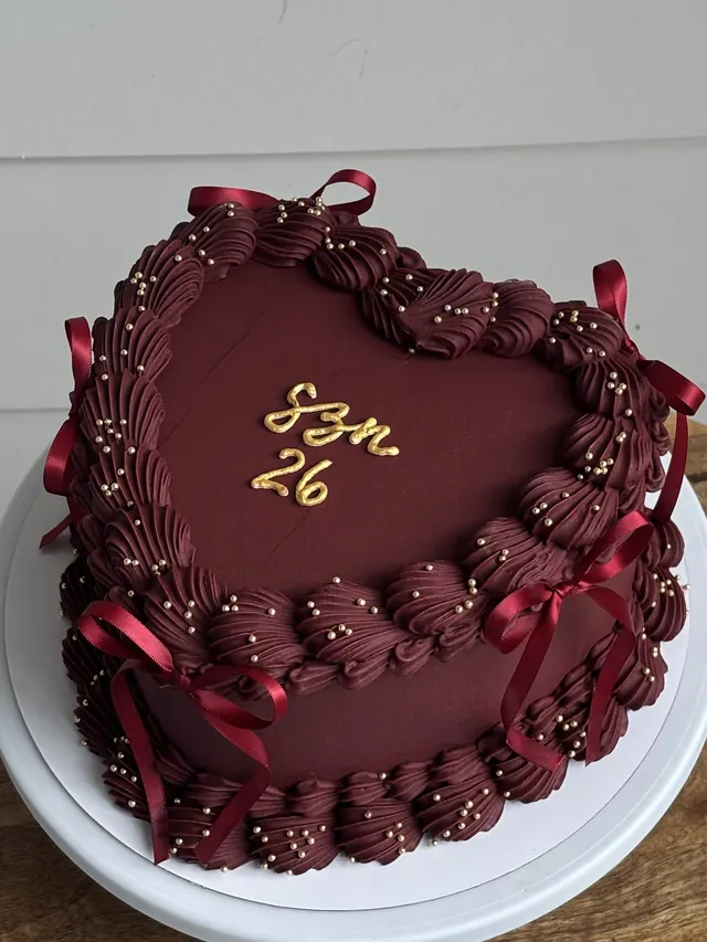 Burgundy heart cake with gold pearls, burgundy bows and "SZN 26."