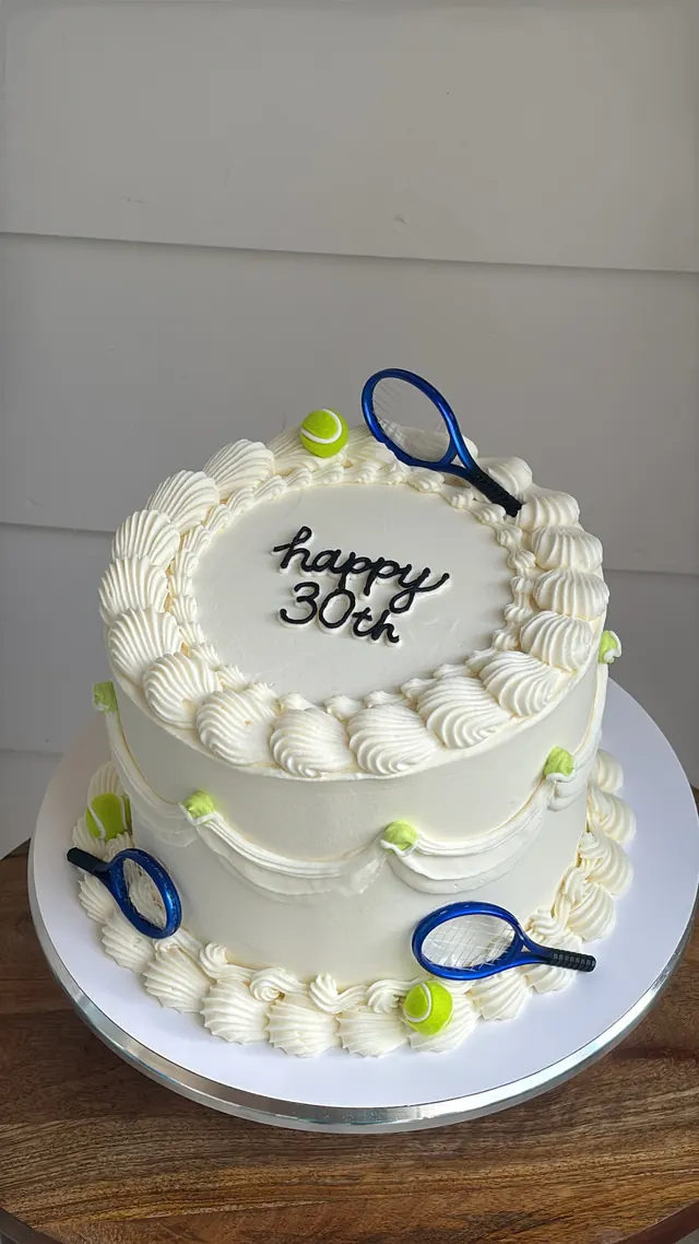 White round cake with tennis rackets and balls and "happy 30th."