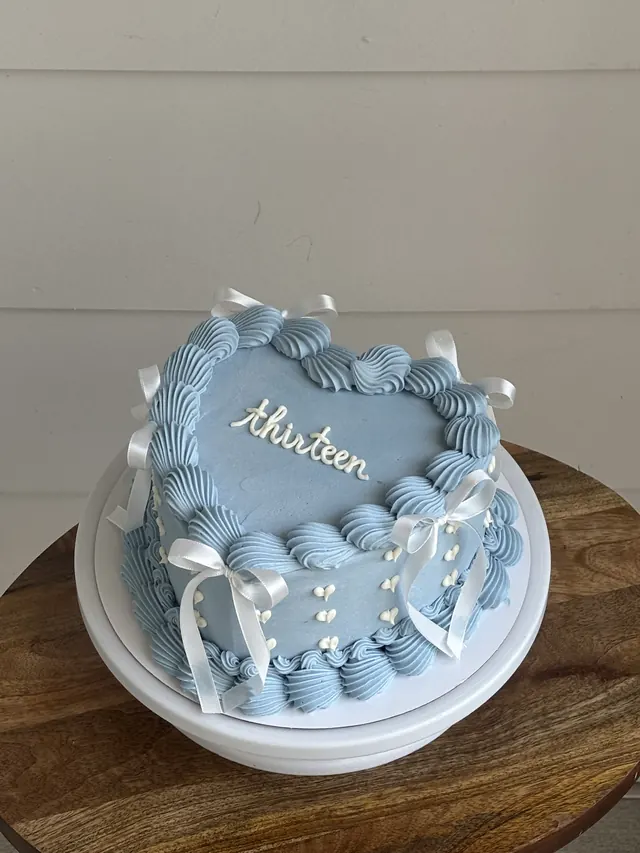 Light blue heart cake with white bows and "thirteen."