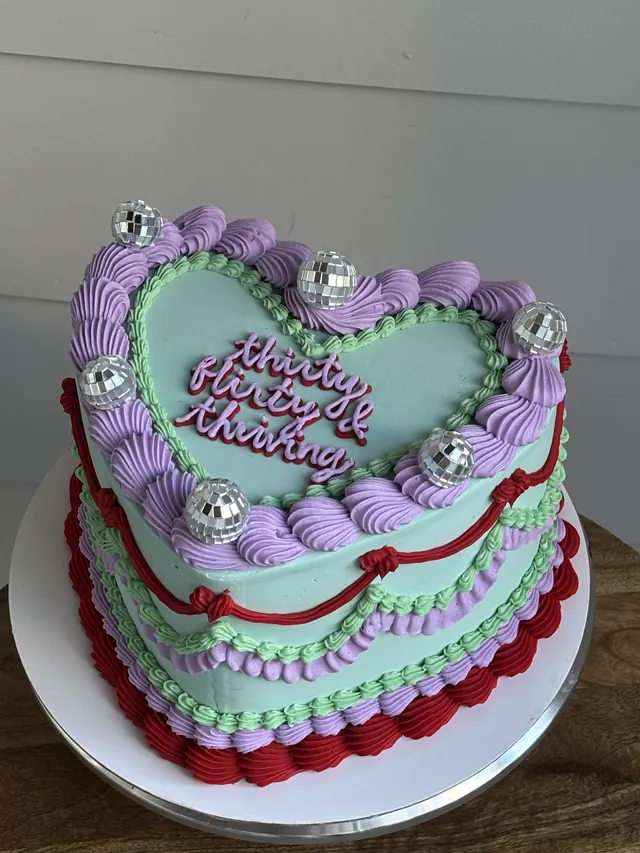 Mint heart cake with lavender and red piping, disco balls and "thirty flirty & thriving."