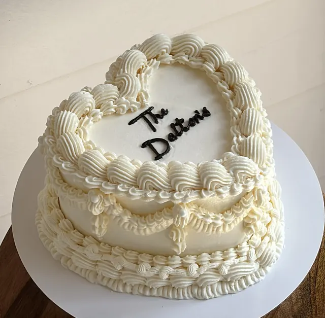 Ivory heart cake with drape piping and the couple's family name