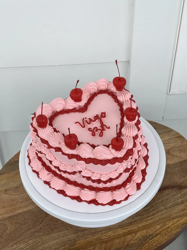 Pink heart cake with red piping, cherries and "Virgo szn."