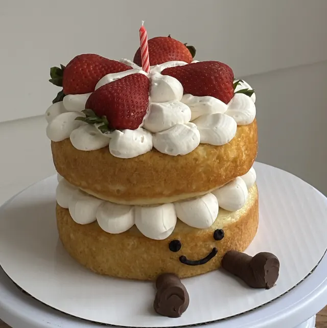 Two-layer shortcake with whipped cream, strawberries and a smiley face