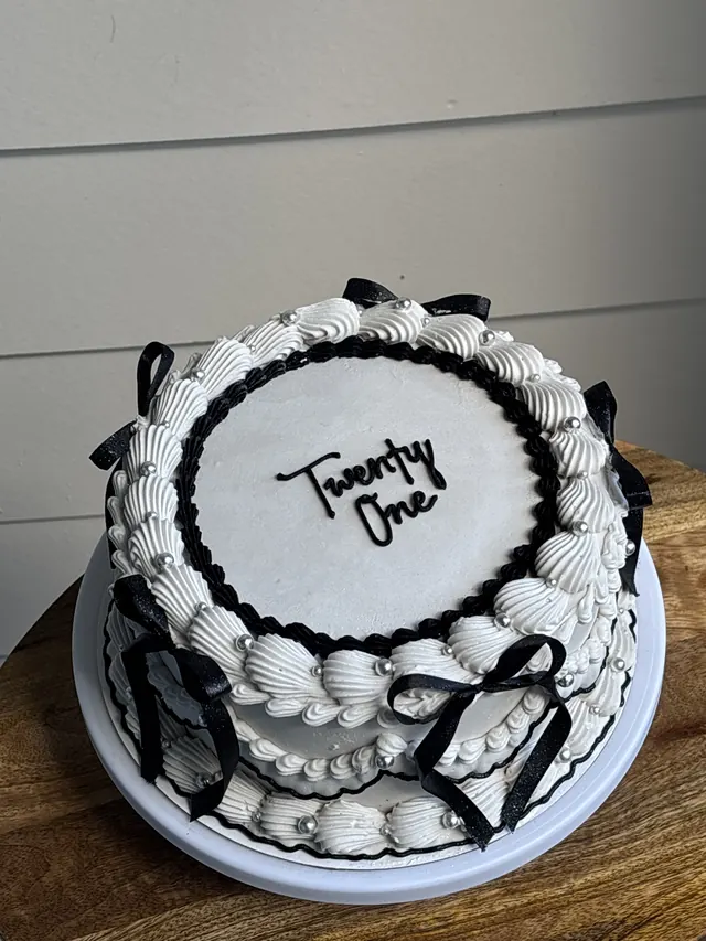 White round cake with black piping, black bows and "Twenty One."