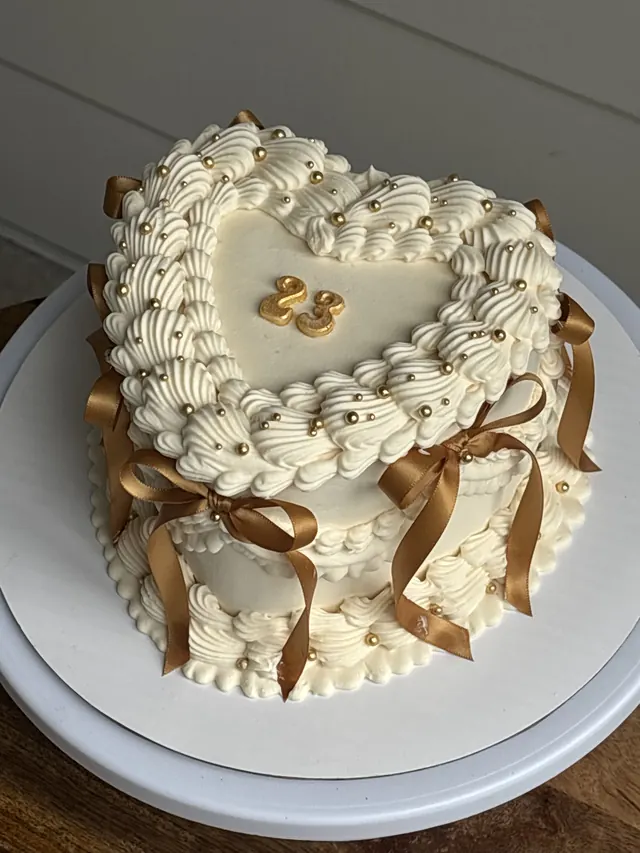 Ivory heart cake with gold pearls, gold satin bows and a gold 23