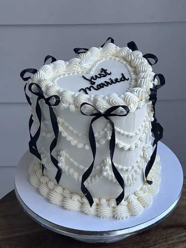 Tall ivory heart cake with black bows and "just married."
