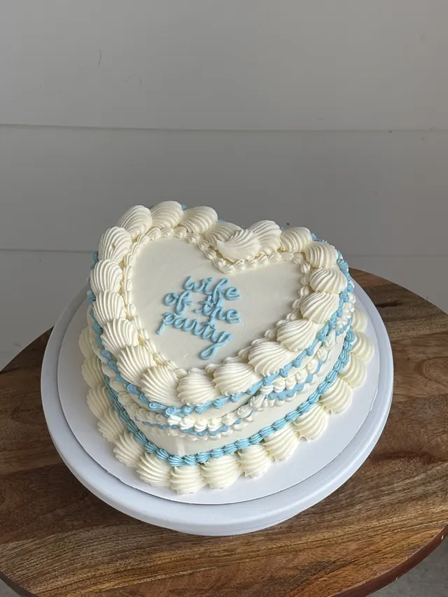 Ivory heart cake with blue piping and "wife of the party."